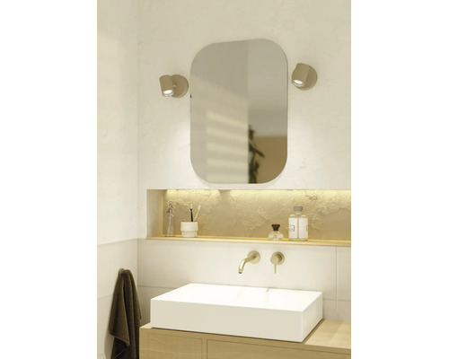 Modernes, helles Badezimmer mit weißem Aufsatzwaschbecken, Holzunterschrank, Wandarmatur, abgerundetem Spiegel und zwei Wandleuchten.
