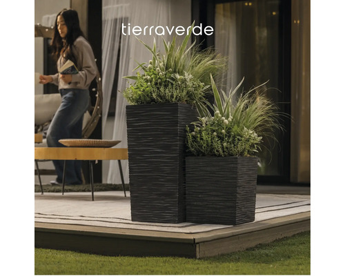 Tierra Verde Logo. Zwei quadratische, strukturierte Pflanzkübel mit Pflanzen auf einer organisierten Terrasse mit Holztisch und Teppich.