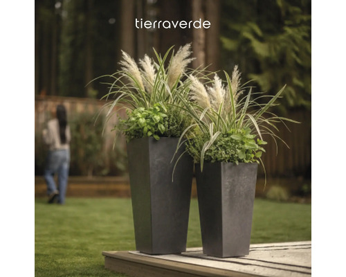 Tierraverde Logo über zwei hohen, konischen quadratischen Pflanzgefäßen mit Ziergräsern in einem Garten auf einer Holzterrasse.