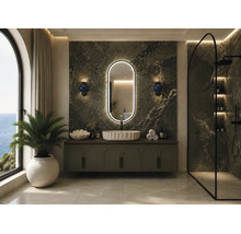 Modernes Badezimmer mit grüner Marmorwand, ovalem beleuchtetem Spiegel, weißem Aufsatzwaschbecken auf einem Unterschrank und einer begehbaren Dusche.
