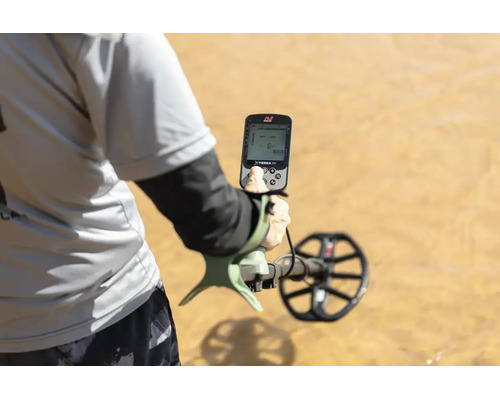 Person verwendet einen Minelab X-TERRA PRO Metalldetektor auf sandigem Untergrund.