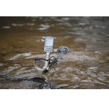 Ein wasserdichter Metalldetektor mit digitalem Display, der teilweise in fließendes Wasser getaucht ist.