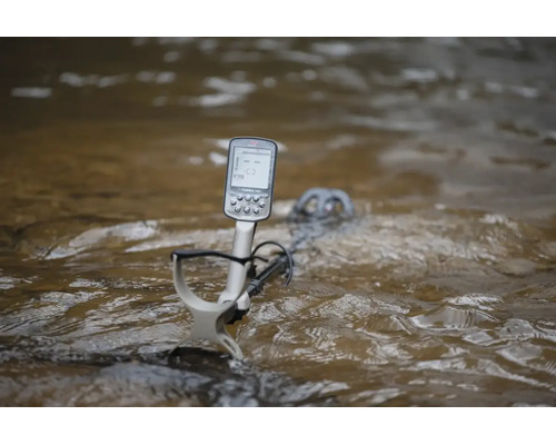 Ein wasserdichter Metalldetektor mit digitalem Display, der teilweise in fließendes Wasser getaucht ist.