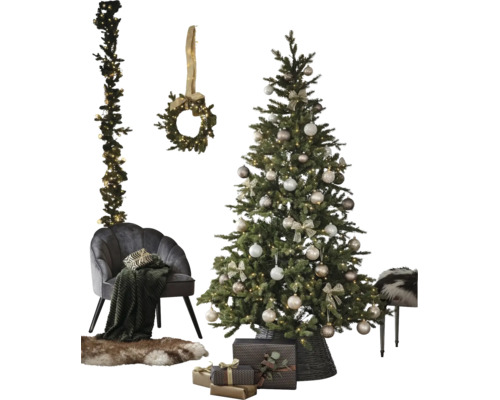 Festlich dekorierter Weihnachtsbaum im Korb, grauer Samtsessel mit Decke, Fellteppich, Geschenke sowie Kranz und Girlande an der Wand.