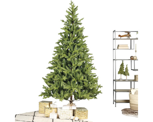 Künstlicher Weihnachtsbaum in einem hellen Raum mit verpackten Geschenken, einem modernen Metallregal und einem Teppich mit Rautenmuster.