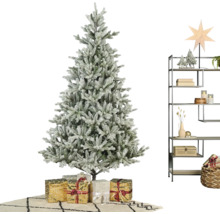 Künstlicher Weihnachtsbaum in Schneeoptik mit Geschenken und einem Metallregal mit winterlicher Dekoration in einem hellen Raum.