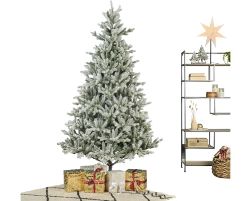 Künstlicher Weihnachtsbaum in Schneeoptik mit Geschenken und einem Metallregal mit winterlicher Dekoration in einem hellen Raum.
