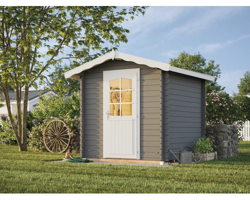 Graues Gartenhaus aus Holz mit weißem Satteldach und weißer Tür mit Sprossenfenster, platziert in einem Garten mit einem Wagenrad und einer Gießkanne.