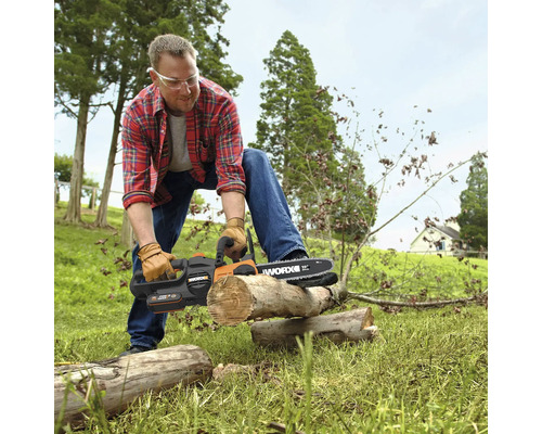 Mann mit Schutzbrille und Handschuhen beim Zersägen eines Holzstamms mit einer Worx Akku-Kettensäge im Freien.