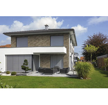 Modernes zweistöckiges Haus mit Außenjalousien an Fenstern und Terrasse, Klinkerfassade sowie Garten mit Lounge-Möbeln und Rasenfläche.