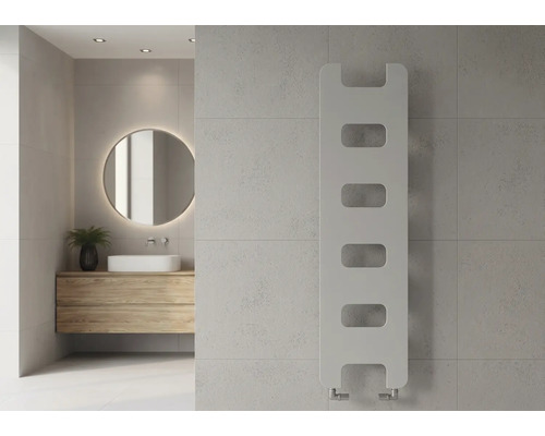Moderner vertikaler Design-Heizkörper mit Aussparungen an einer Fliesenwand im hellen Badezimmer mit Holzwaschtisch und rundem Spiegel.