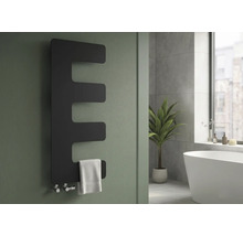 E-förmiger Design-Badheizkörper in Matt-Optik an einer Wand mit weißem Handtuch in einem hellen, modernen Badezimmer.