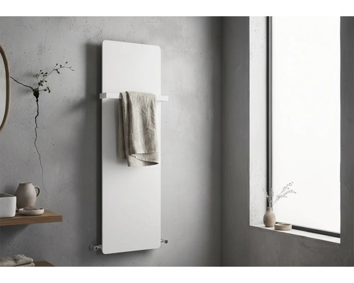 Moderner weißer Planheizkörper an einer Betonwand in einem minimalistischen Badezimmer, mit Handtuchhalter und aufgehängtem Handtuch.