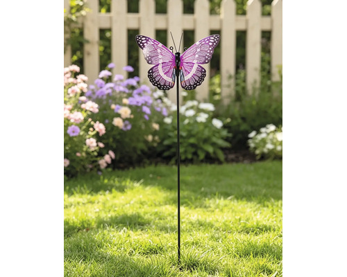 Gartenstecker mit einem lilafarbenen Schmetterling auf einem Rasen vor Blumen und einem hellen Holzzaun.