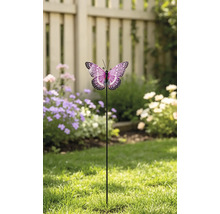 Dekorativer Gartenstecker Schmetterling mit gemusterten Flügeln auf einem Metallstab, platziert auf einem Rasen vor einem Gartenzaun und Blumen.