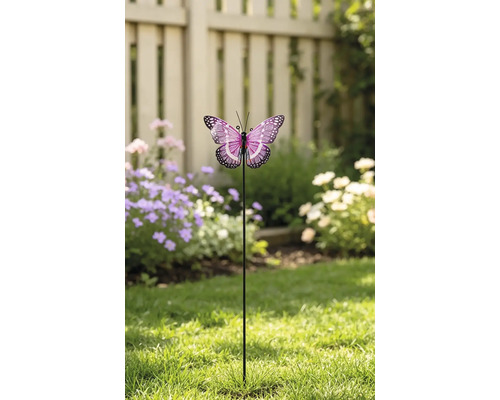 Dekorativer Gartenstecker Schmetterling mit gemusterten Flügeln auf einem Metallstab, platziert auf einem Rasen vor einem Gartenzaun und Blumen.