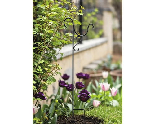 Schwarzer Gartenstab aus Metall mit drei Haken für Blumenampeln oder Vogelfutterhäuser, stehend in einem Blumenbeet.
