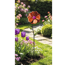 Gartenstecker aus Metall in Form einer Blume mit zwei Blättern in einem bepflanzten Gartenbeet.