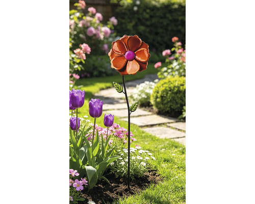 Gartenstecker aus Metall in Form einer Blume mit zwei Blättern in einem bepflanzten Gartenbeet.