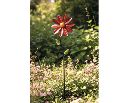 Gartenstecker aus Metall in Form einer Blume mit roten Blütenblättern in einem hellen Gartenbeet.