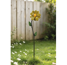 Helle Außenszene mit einem dekorativen Gartenstecker aus Metall in Form einer Blume mit Blättern, der in einem Rasen vor einem Zaun steht.