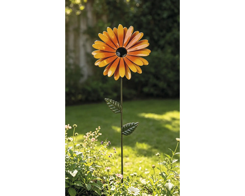 Gartenstecker aus Metall in Form einer orangefarbenen Blume mit schwarzer Mitte und grünem Stiel mit Blättern in einem Garten.