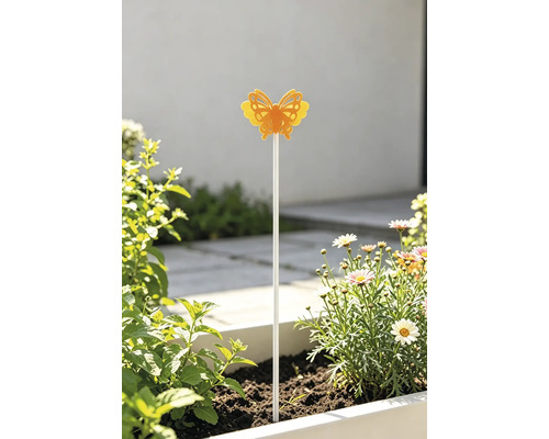 Heller, sonniger Außenbereich mit einem gelben Schmetterlings-Gartenstecker in einem Blumenkasten mit Margeriten und grünen Pflanzen.