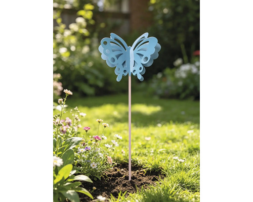 Dekorativer Gartenstecker in Schmetterlingsform mit Ausschnitten auf einem Stab, platziert in einem hellen Gartenbeet mit Blumen und Gras.