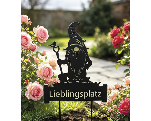 Gartenstecker aus schwarzem Metall mit Gartenzwerg-Silhouette, Schaufel, Vogel und Schriftzug Lieblingsplatz, platziert in einem Rosenbeet.