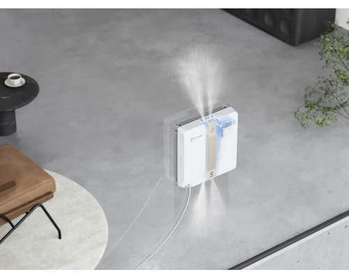 Ein automatischer Fensterputzroboter von Ecovacs, der Wasser auf die Glasfläche sprüht, um diese effizient zu reinigen.