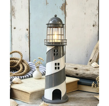 Dekorativer Teelichthalter als Leuchtturm mit Spiralmuster und brennender Kerze in einer maritimen Szene mit Seil, Büchern und Muscheln.