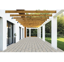 Moderne Terrasse mit Pflastersteinen, einer Holzpergola mit horizontalen Balken und weißen Säulen neben einem Garten.