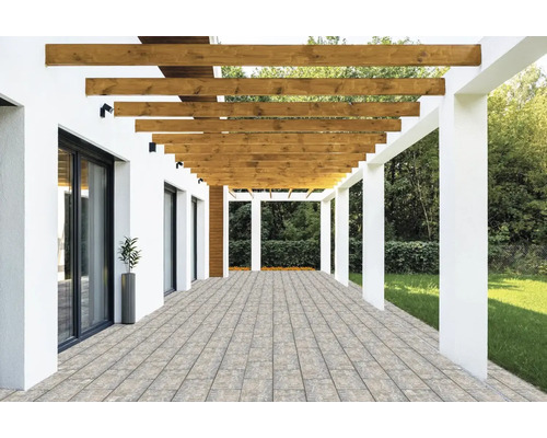 Moderne Terrasse mit Pflastersteinen, einer Holzpergola mit horizontalen Balken und weißen Säulen neben einem Garten.