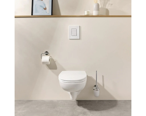Modernes Wand-WC mit geschlossenem Deckel, Drückerplatte, Toilettenpapierhalter und Klobürste in einem minimalistischen Badezimmer.