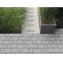 Moderne Gartengestaltung mit Pflastersteinen aus Beton, einem Kiesweg mit Trittsteinen, Ziergräsern und einem großen Pflanzgefäß.