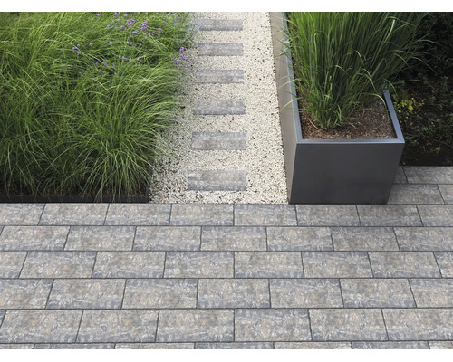 Moderne Gartengestaltung mit Pflastersteinen aus Beton, einem Kiesweg mit Trittsteinen, Ziergräsern und einem großen Pflanzgefäß.