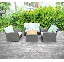 Terrasse mit grauen rechteckigen Steinplatten, einer Polyrattan-Gartenlounge und einem Holztisch vor grüner Bepflanzung.