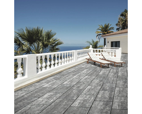 Moderne Terrasse mit grauen Terrassenplatten in Steinoptik, weißer Balustrade, Sonnenliegen und Meerblick in hellem mediterranem Ambiente.