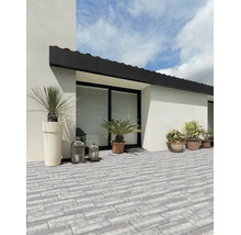Helle, organisierte Terrasse mit modernen, grauen Pflastersteinen in Rechteckform, dekoriert mit Pflanzgefäßen und Laternen an einer weißen Fassade.