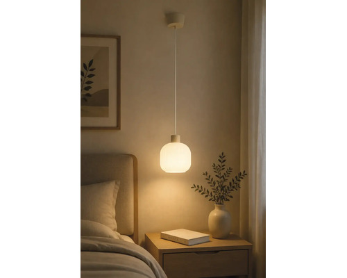 Pendelleuchte mit rundem Schirm aus mattem Glas, hängend über einem Nachttisch aus Holz in einem Schlafzimmer.