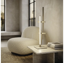 Moderne LED-Tischleuchte im minimalistischen Design auf einem Steintisch neben einem weißen Bouclé-Sessel in einem hellen Wohnraum.