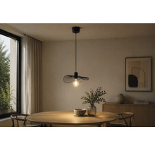 Moderne schwarze Pendelleuchte aus Drahtgeflecht über einem runden Esstisch aus Holz in einem hellen Zimmer mit Anrichte und Pflanzen.