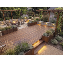 Moderne Gartengestaltung mit Holzterrasse, Steinmauer mit Beleuchtung, Feuerstelle, Adirondack-Stühlen, Pergola und bepflanzten Beeten.