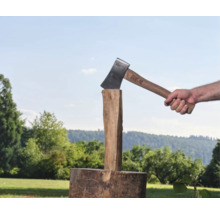Eine Person spaltet mit einer For Q Spaltaxt einen Holzstamm auf einem Hackstock im Freien.