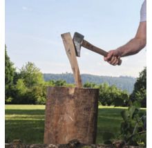 Eine Person spaltet mit einer For Q Spaltaxt ein Stück Holz auf einem Hackklotz im Freien.
