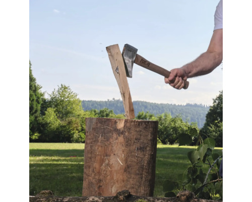 Eine Person spaltet mit einer For Q Spaltaxt ein Stück Holz auf einem Hackklotz im Freien.