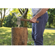 Eine Person benutzt eine For-Q Axt mit Holzstiel, um einen Holzstamm im Freien zu spalten.
