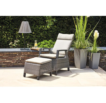 Gartensessel-Set aus Polyrattan mit Hocker und hellen Auflagen auf einer modernen Terrasse mit hohen Pflanzgefäßen.
