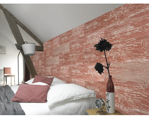 Helles Schlafzimmer mit strukturierter Wand in roter Holzoptik, weißem Bettzeug, rustikalem Holzbalken und einer modernen Stehlampe.