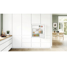 Einbaukühlschrank von Bosch mit offener Tür in einer modernen hellen Küche mit weißen Fronten und Holzfußboden.
